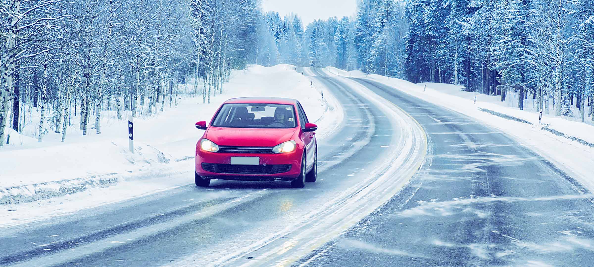 Red car driving on a snowy winter road